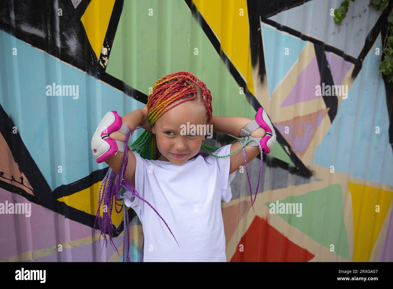 portrait d'une petite belle fille avec des tresses africaines multicolores sur le fond d'un mur coloré Banque D'Images