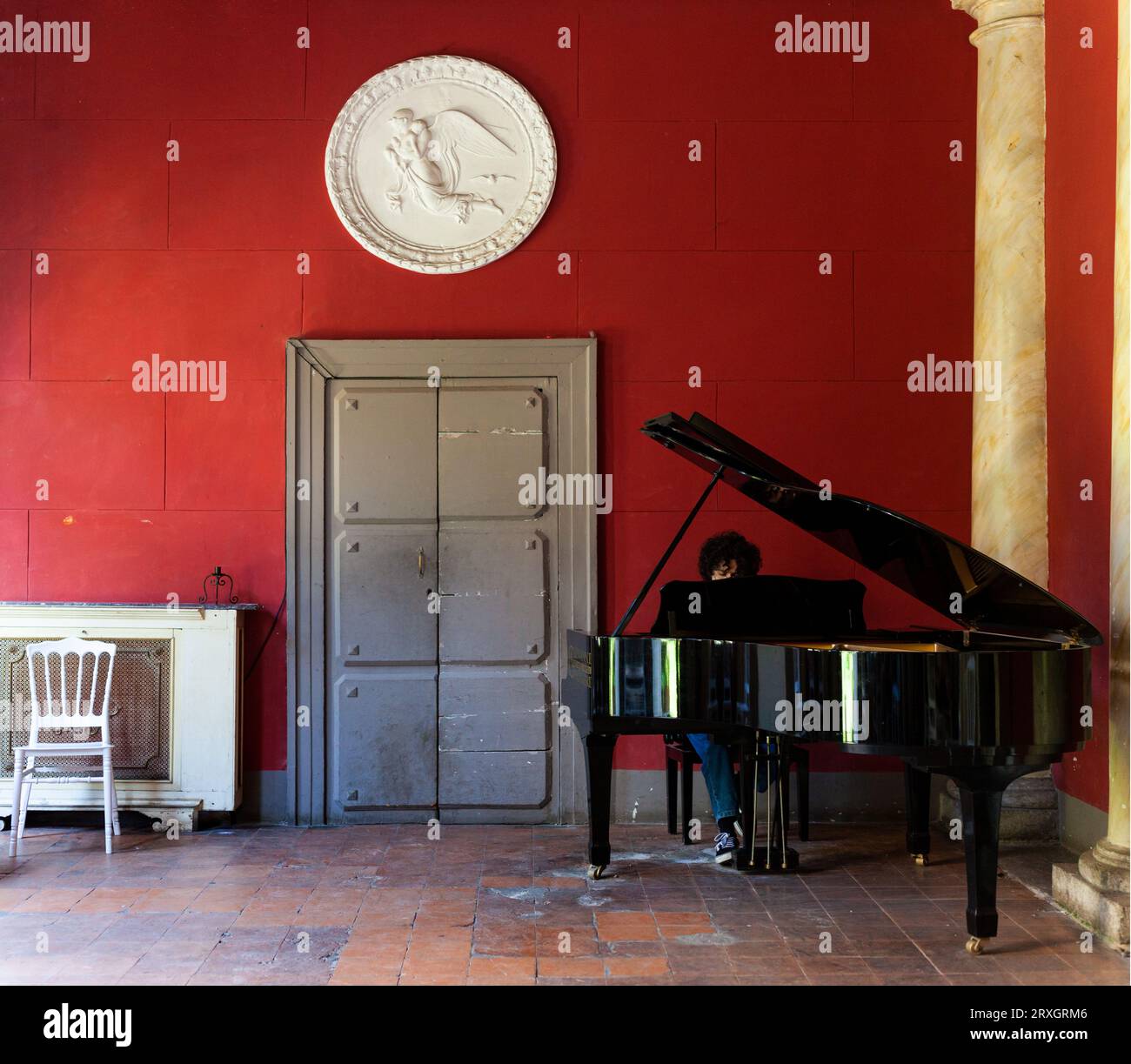 Naples, Italie - 16 juin 2023 : garçon jouant du piano dans la salle rouge appelée Casina Pompeiana dans le Palazzo Venezia Banque D'Images