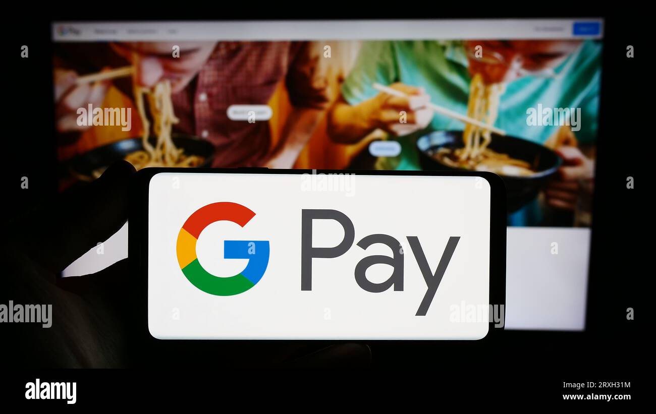 Personne détenant smartphone avec logo du service de paiement mobile Google Pay sur l'écran en face du site Web. Concentrez-vous sur l'affichage du téléphone. Banque D'Images
