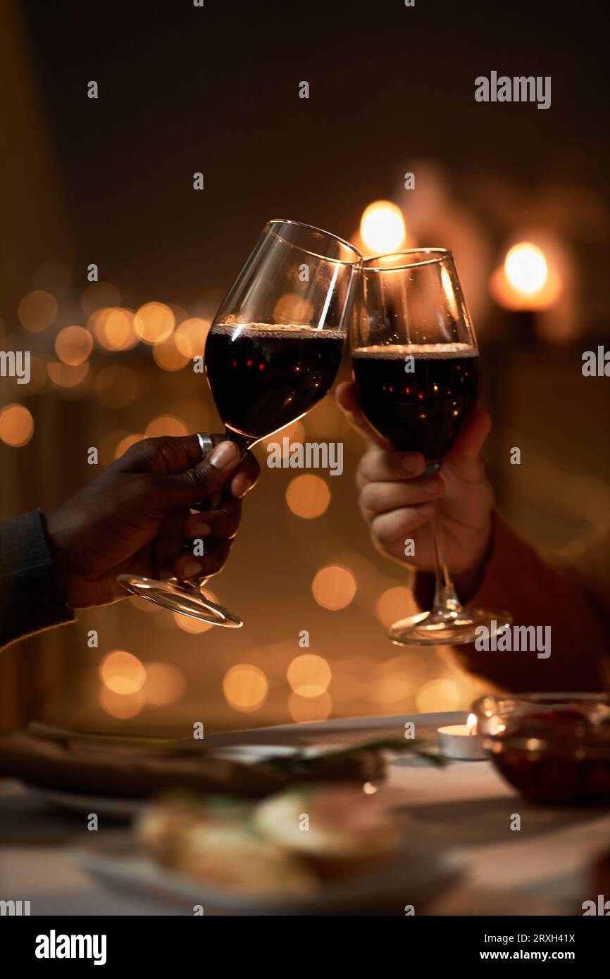 Gros plan de couple multiethnique toasting avec des verres à vin à la table de dîner romantique au cours de la date Banque D'Images