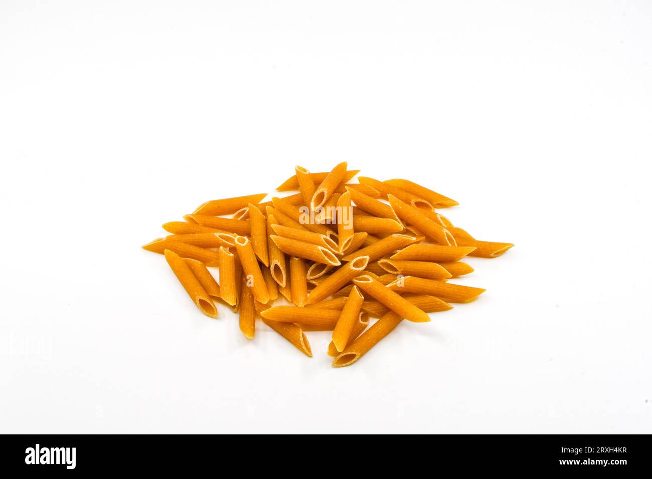 Tas de tubes de pâtes à penne complètes séchées isolés sur fond blanc Uni. Espace de copie. Banque D'Images