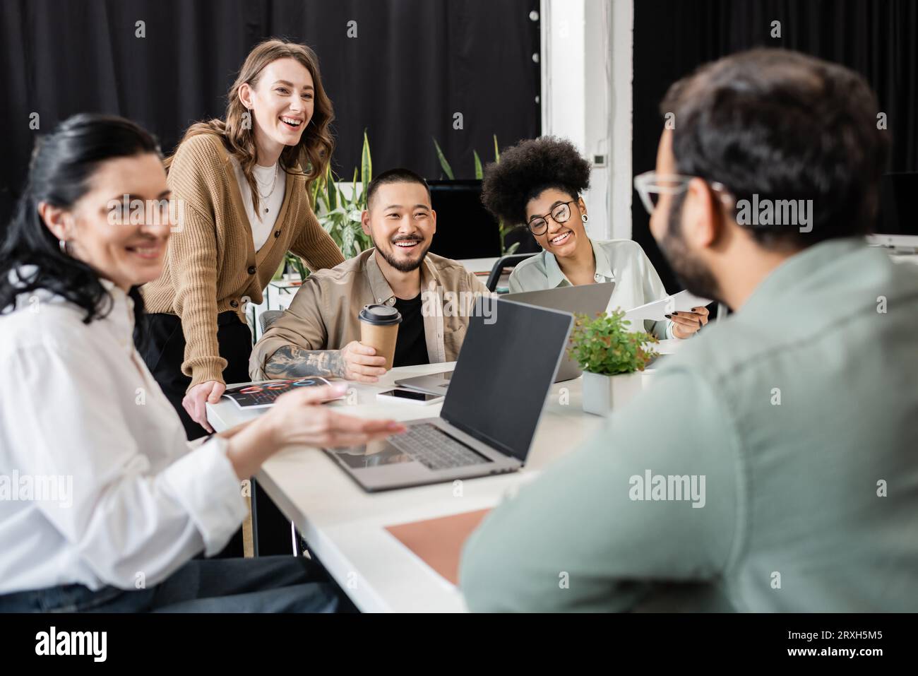 heureuse équipe interraciale d'affaires regardant le collègue sur le premier plan flou, brainstorming Banque D'Images