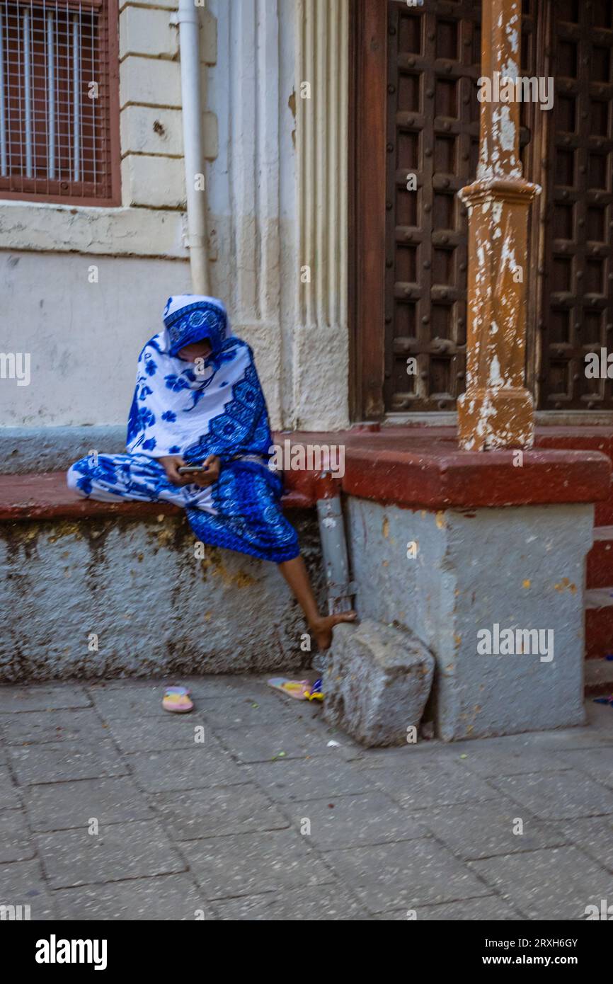 Femme africaine musulmane assise dans le chador bleu hijab Stone Town, Zanzibar, Tanzanie Banque D'Images