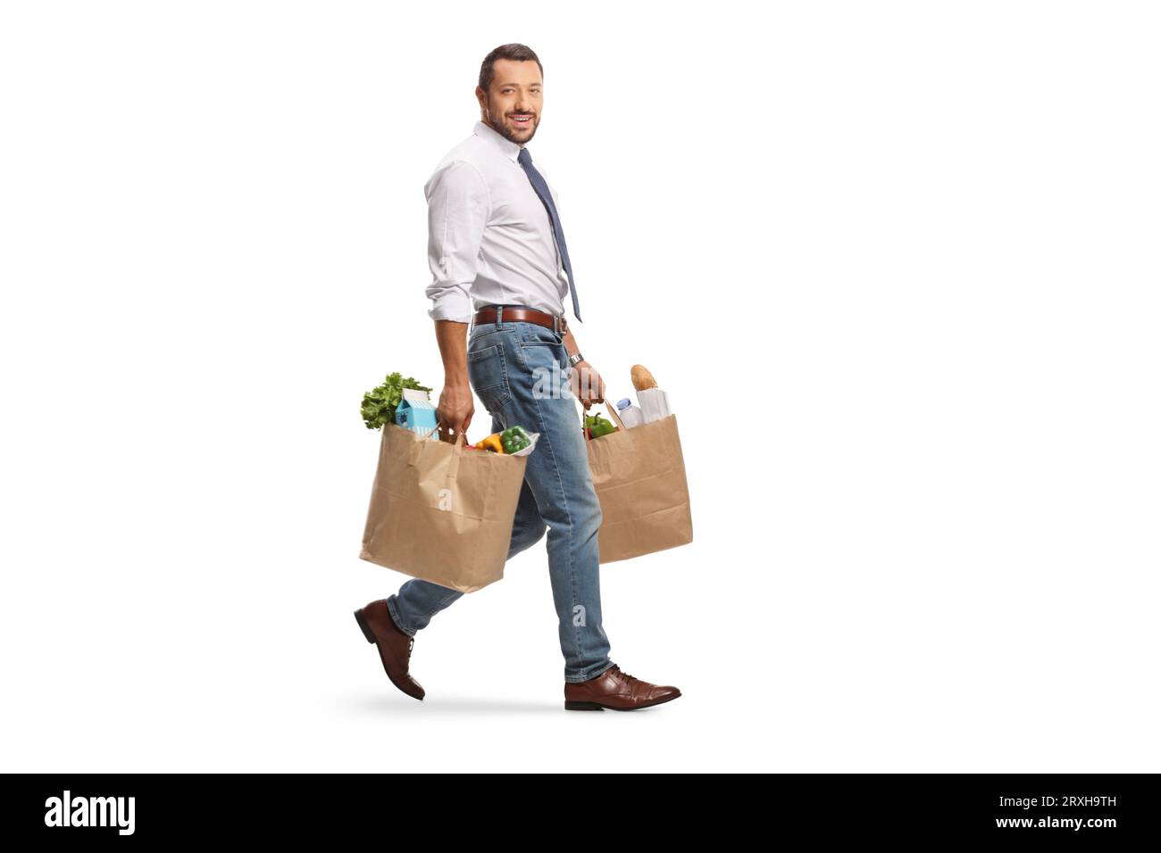 Plan en longueur d'un homme d'affaires marchant avec des sacs d'épicerie et regardant la caméra isolée sur fond blanc Banque D'Images