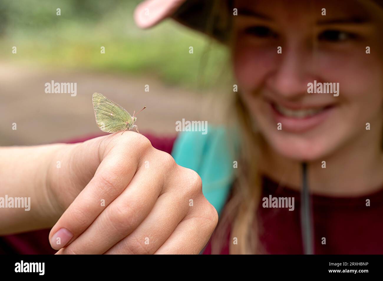 Gros plan d'une jeune fille regardant la papillons de nuit (lépidoptère) qui a atterri sur sa main ; Yukon, Canada Banque D'Images