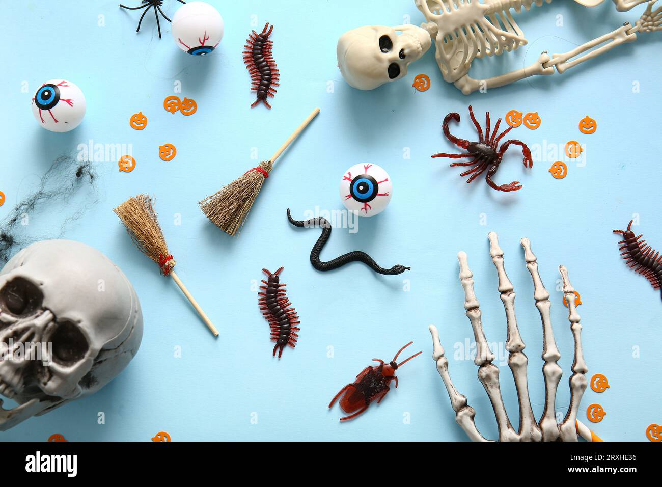 Composition d'Halloween avec des insectes de bonbons, des squelettes et des globes oculaires sur fond bleu Banque D'Images