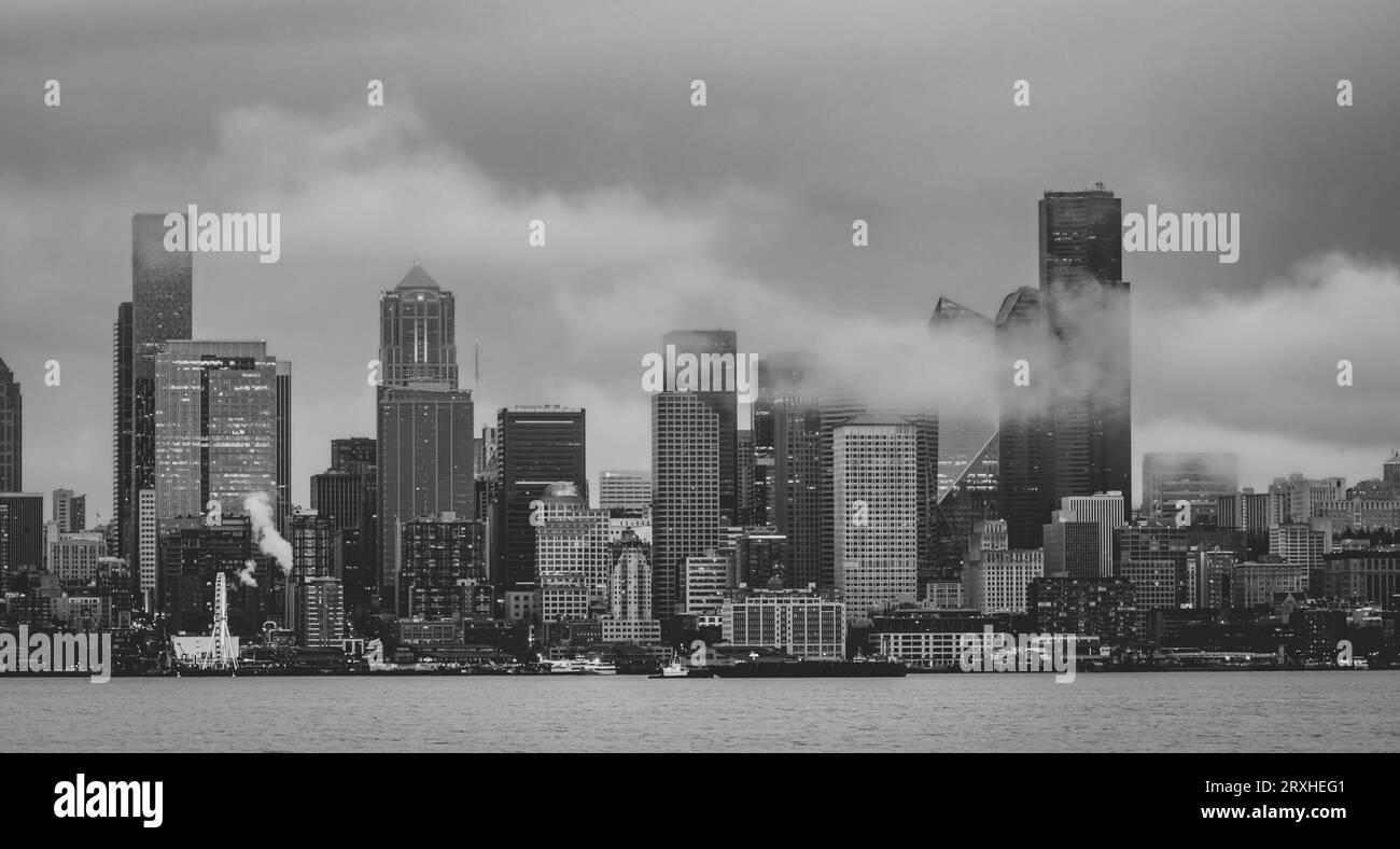 Les gratte-ciel de Seattle forment West Seattle à travers Elliott Bay par un après-midi pluvieux avec des nuages bas et du brouillard qui dérive à travers les grands bâtiments Banque D'Images