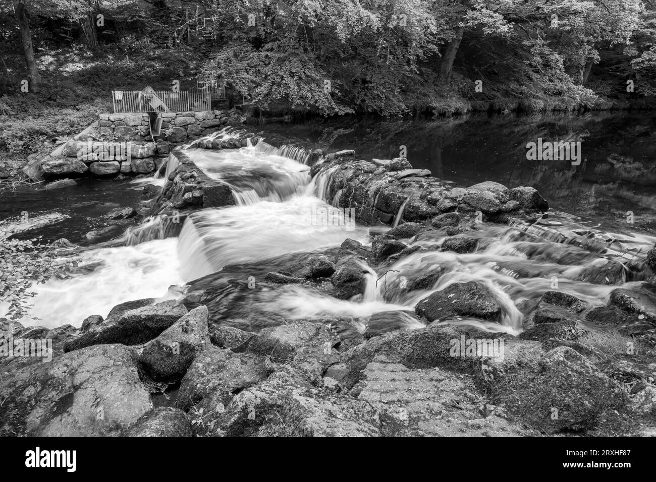 Longue exposition de la rivière Teign qui coule à travers le déversoir du château de Drogo dans le parc national de Dartmoor Banque D'Images