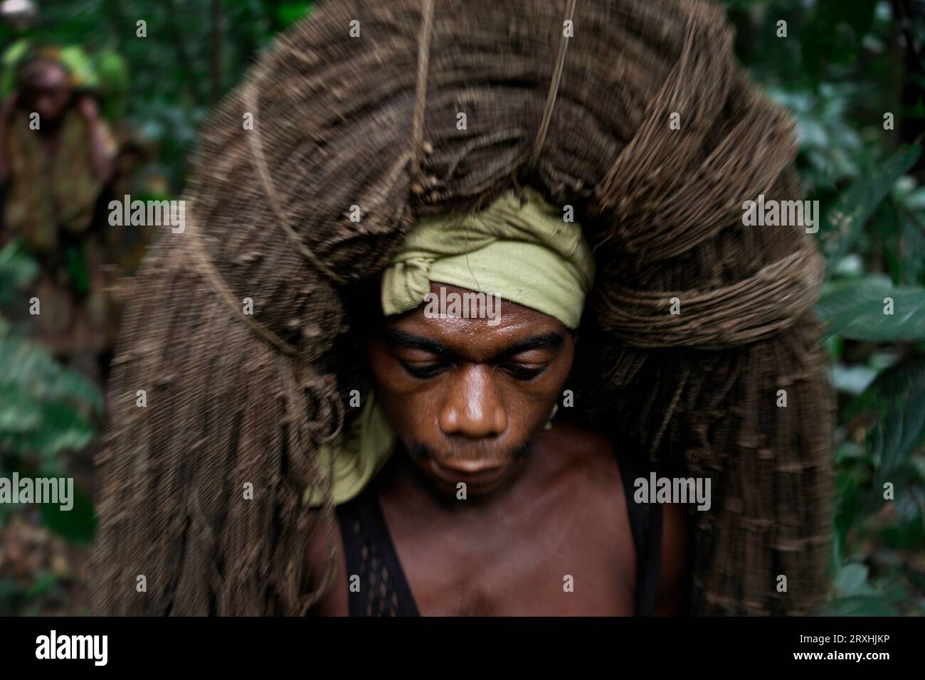 Un chasseur Mbuti porte un filet d'écorce de liane torsadée sur sa tête qui sert de filet pour capturer des proies alors que la tribu semi-nomade se déplace dans l'Ituri Banque D'Images