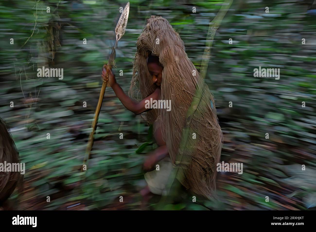 Chasseur pygmée Mbuti avec lance et filet roulé pour le gibier au collant. ; Forêt d'Ituri, Congo. Banque D'Images