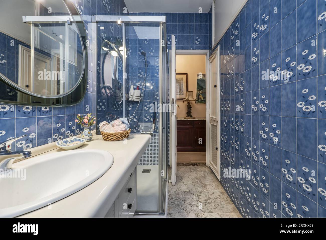 salle de bains avec meuble en bois avec lavabo en porcelaine blanche, cabine de douche et carrelage bleu vintage sur les murs Banque D'Images