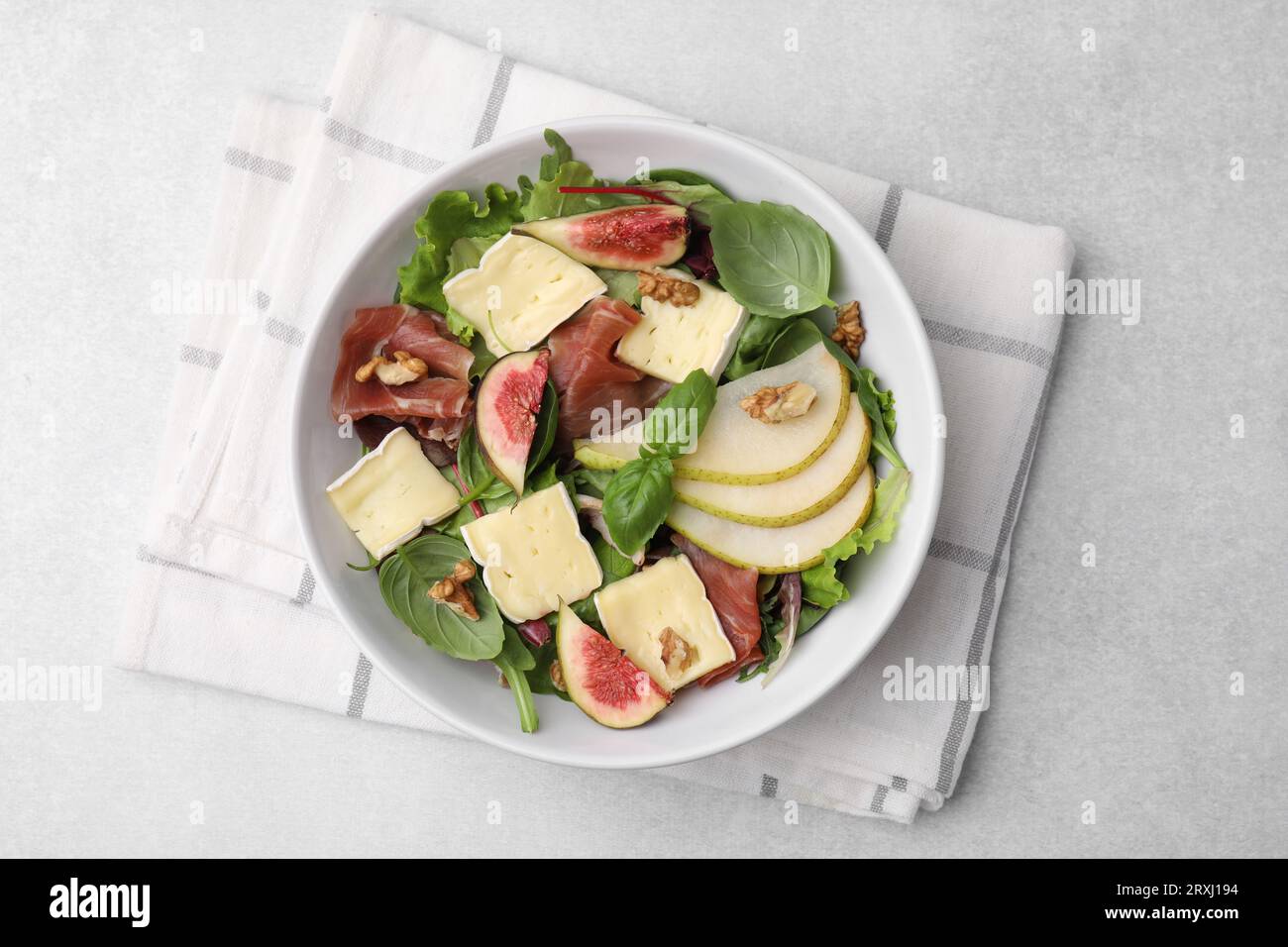 Salade savoureuse avec fromage brie, prosciutto, poire et figues sur table gris clair, vue de dessus Banque D'Images