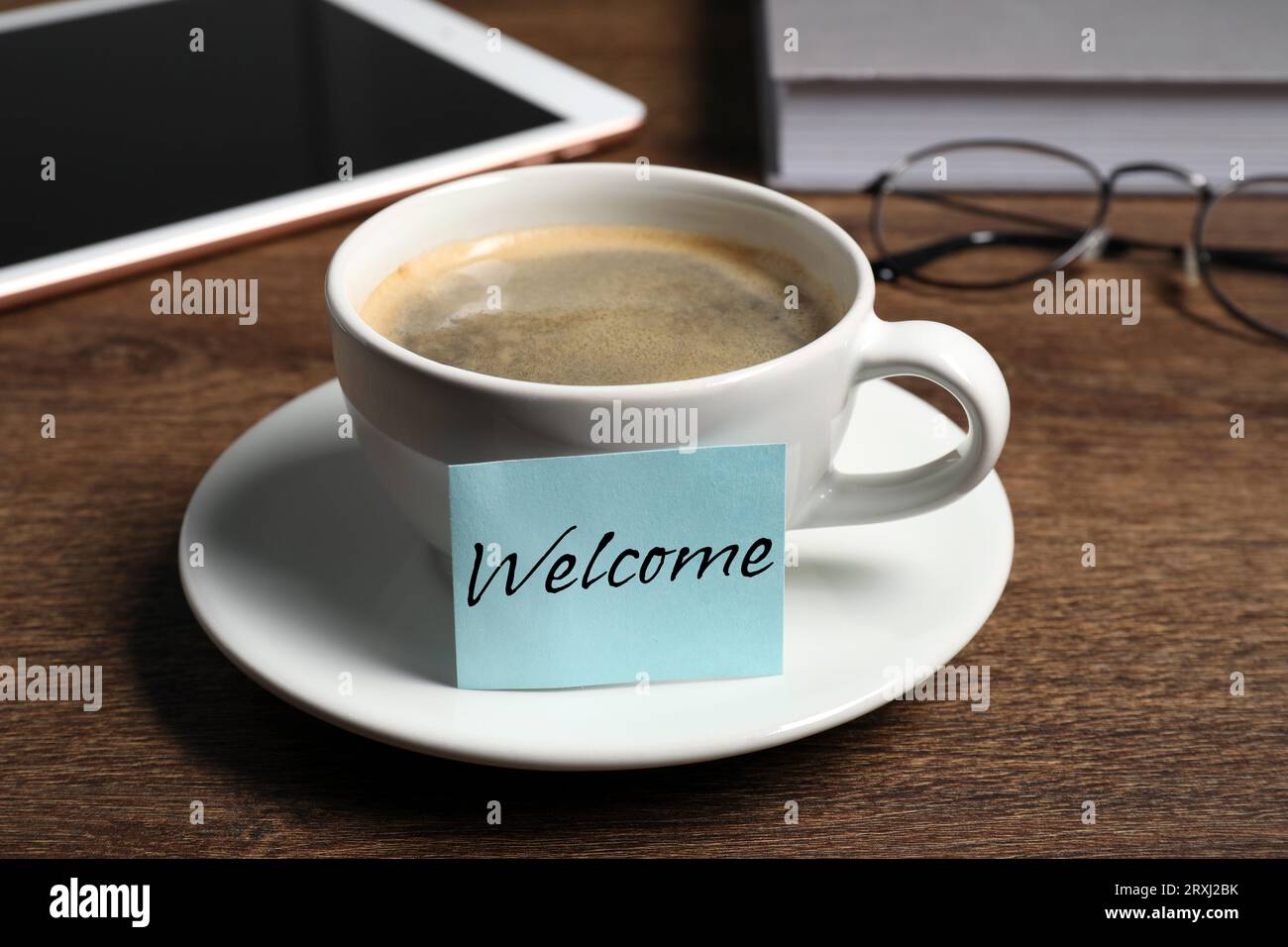 Note collante avec mot Bienvenue attaché à la tasse de café sur le bureau en bois Banque D'Images