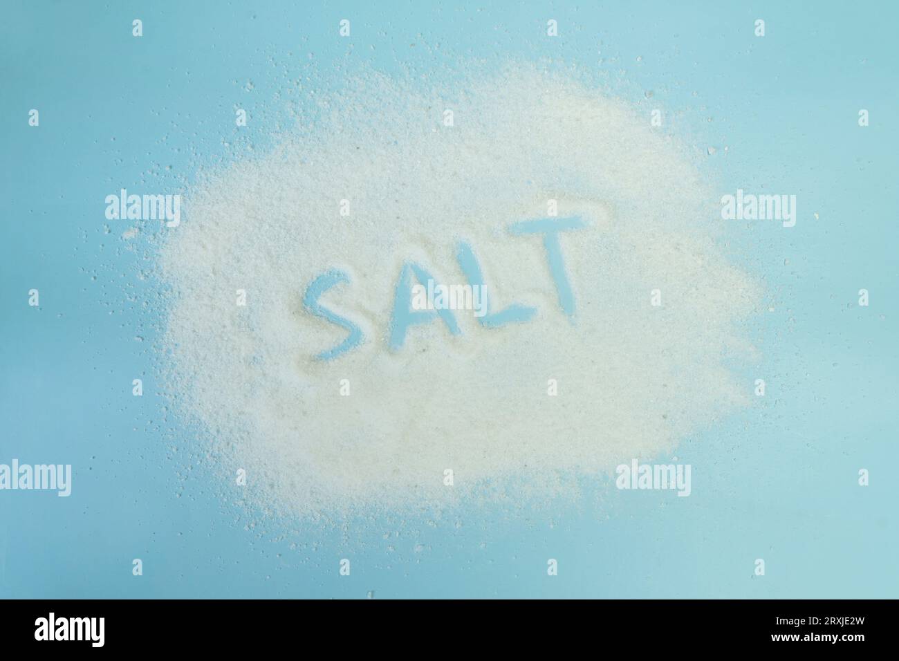 Vue de dessus grain de sel sur fond bleu. le mot sel est écrit avec du sel sur une table bleue. Banque D'Images
