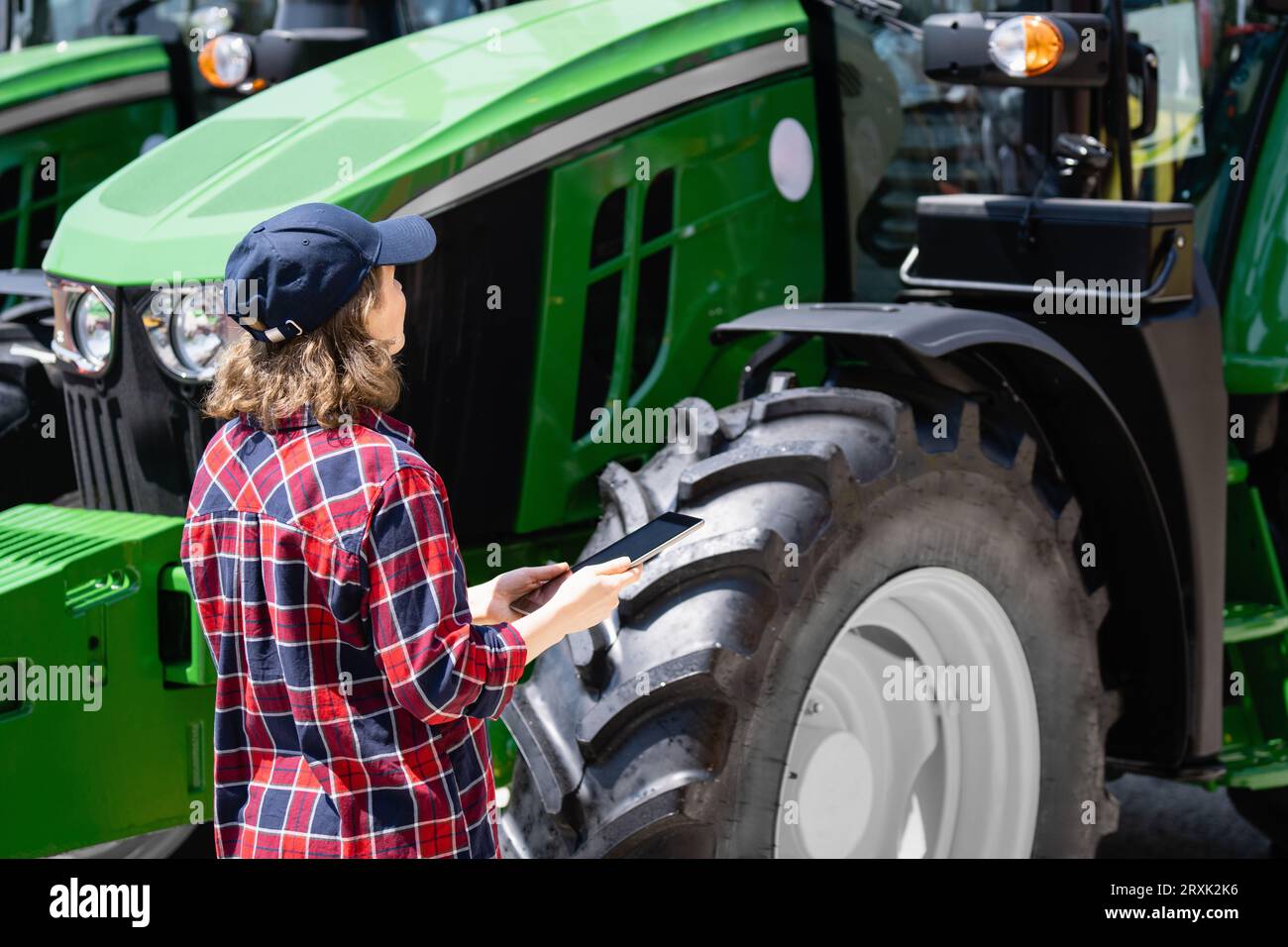 Femme agriculteur avec une tablette numérique sur le fond d'un tracteur agricole. Banque D'Images