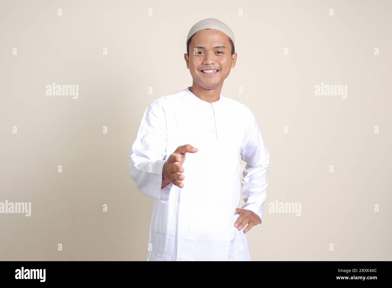 Portrait d'un homme musulman asiatique attrayant en chemise blanche tendant sa main pour une poignée de main, accueillant quelqu'un. Image isolée sur fond gris Banque D'Images