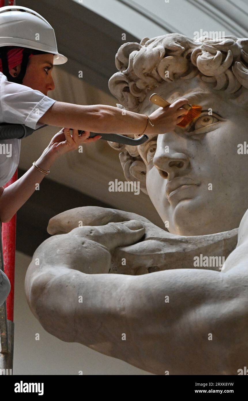 La restauratrice italienne Eleonora Pucci nettoie la poussière et les débris de la célèbre statue de marbre de David de Michel-Ange à la Galleria dell’Accademia à Florence, en Italie, le 25 septembre 2023. Le restaurateur passe une journée à dépoussiérer la statue de 5,17 mètres. Le processus a lieu tous les deux mois. Elle utilise une série de brosses souples et un aspirateur à basse pression pour enlever toujours plus doucement la poussière et les dépôts de saleté qui se produisent inévitablement quand il y a tant de visiteurs qui affluent pour voir les chefs-d'œuvre. La statue a été réalisée par le maître italien entre 1501-1504 à partir d'un bloc de marbre. Il représente le Bi Banque D'Images