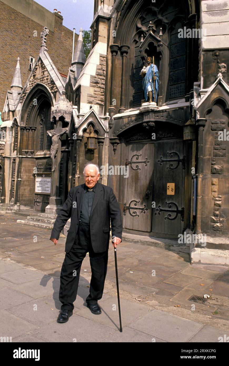 La haute Église anglo-catholique d'Angleterre, l'Église Saint-Jean-Baptiste. Le révérend Phyall quitte l'église après la messe solennelle. Holland Park Road, Shepherd's Bush, Londres, Angleterre 1985. ANNÉES 1980 ROYAUME-UNI HOMER SYKES Banque D'Images