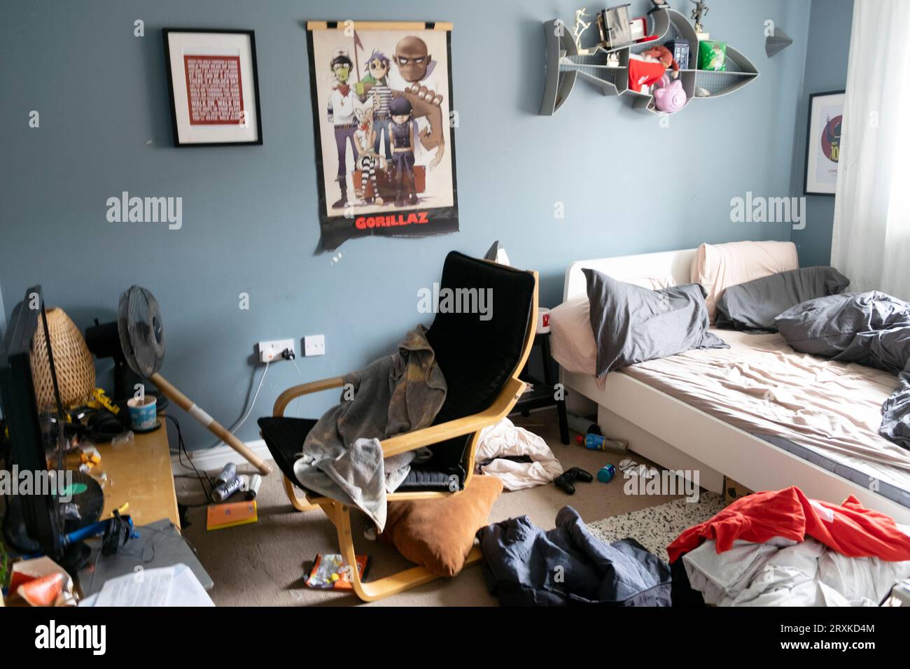 Chambre en désordre de l'adolescent adolescent garçon et vêtements de lit défaits Gorillaz poster chaise gris bleu murs peinture murale peinte Grande-Bretagne UK 2023 KATHY DEWITT Banque D'Images