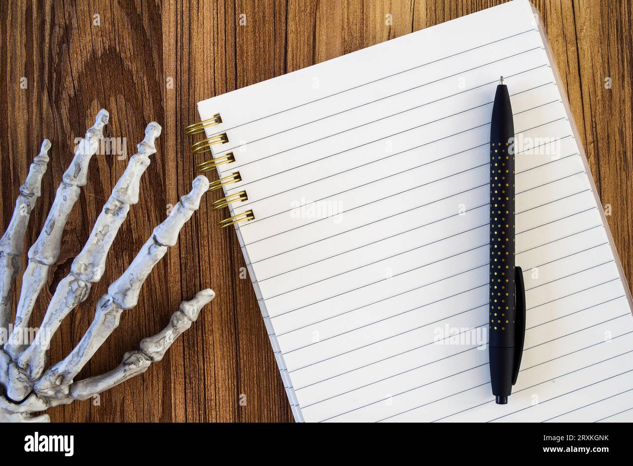 main squelette à côté d'un cahier doublé vierge avec maquette de stylo noir Banque D'Images