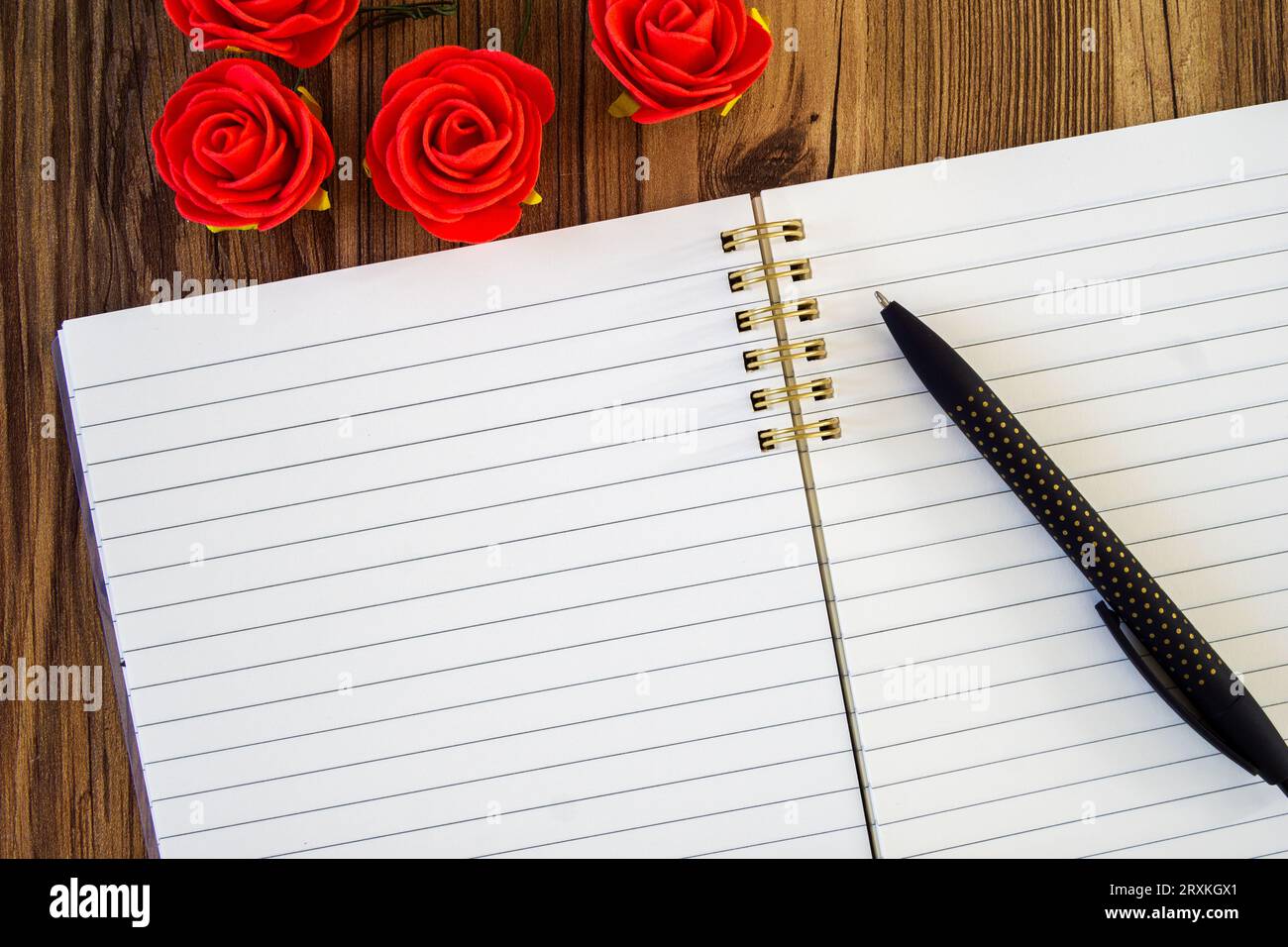 stylo noir sur bloc-notes vierge à doublure ouverte, maquette avec dosettes roses rouges Banque D'Images