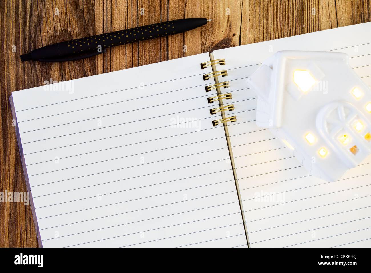 stylo noir à côté d'un bloc-notes vierge doublé ouvert maquette avec maison en céramique Banque D'Images