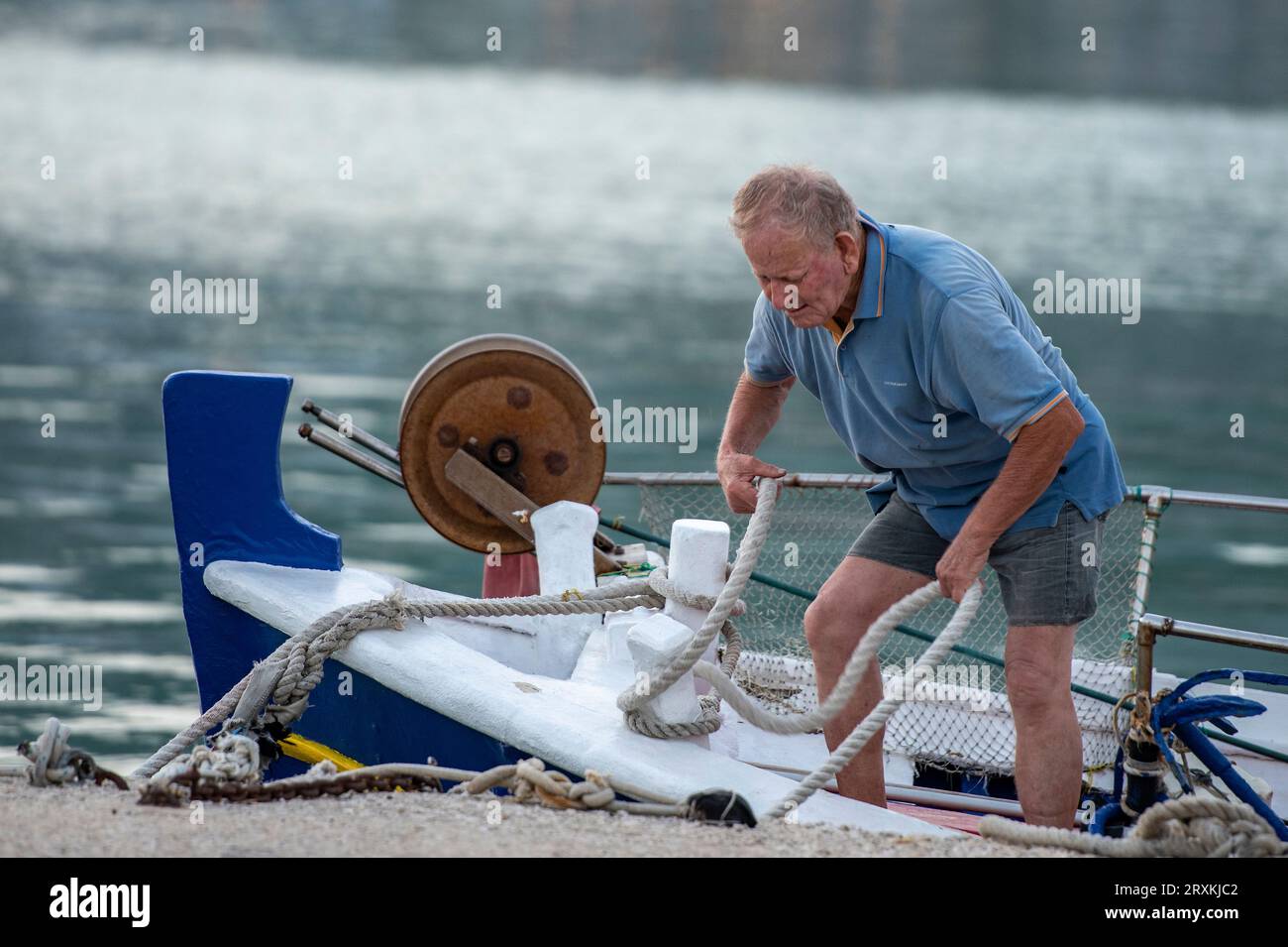vieux pêcheur grec attachant des cordes sur un bateau de pêche dans le port de la ville grecque de zante ou zakynthos. Banque D'Images