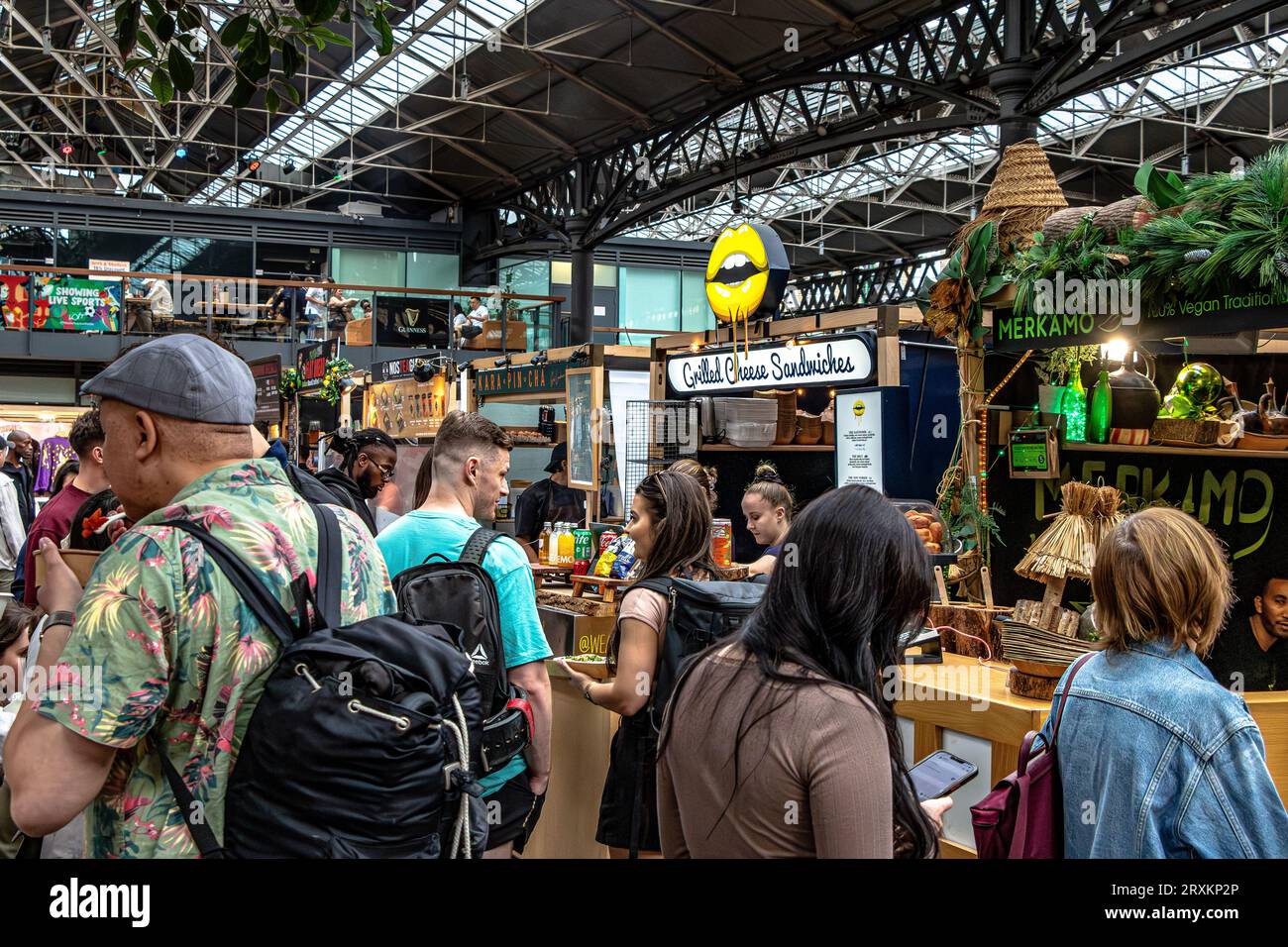 Les gens qui font la queue pour acheter de la nourriture dans les magasins d'alimentation de Old Spitalfields Market, Londres, E1 Banque D'Images