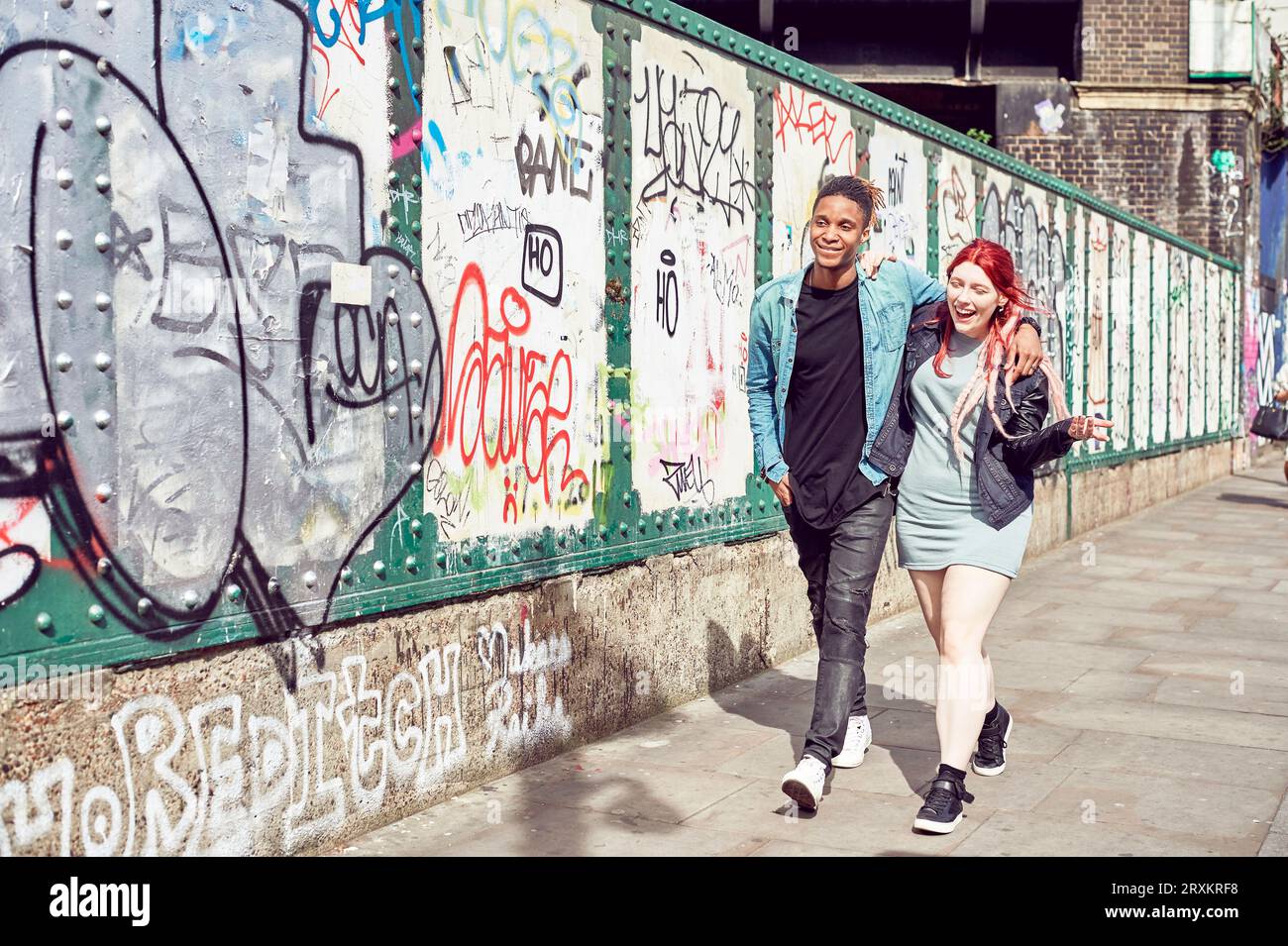 Teenage couple en train de marcher le long des trottoirs Banque D'Images