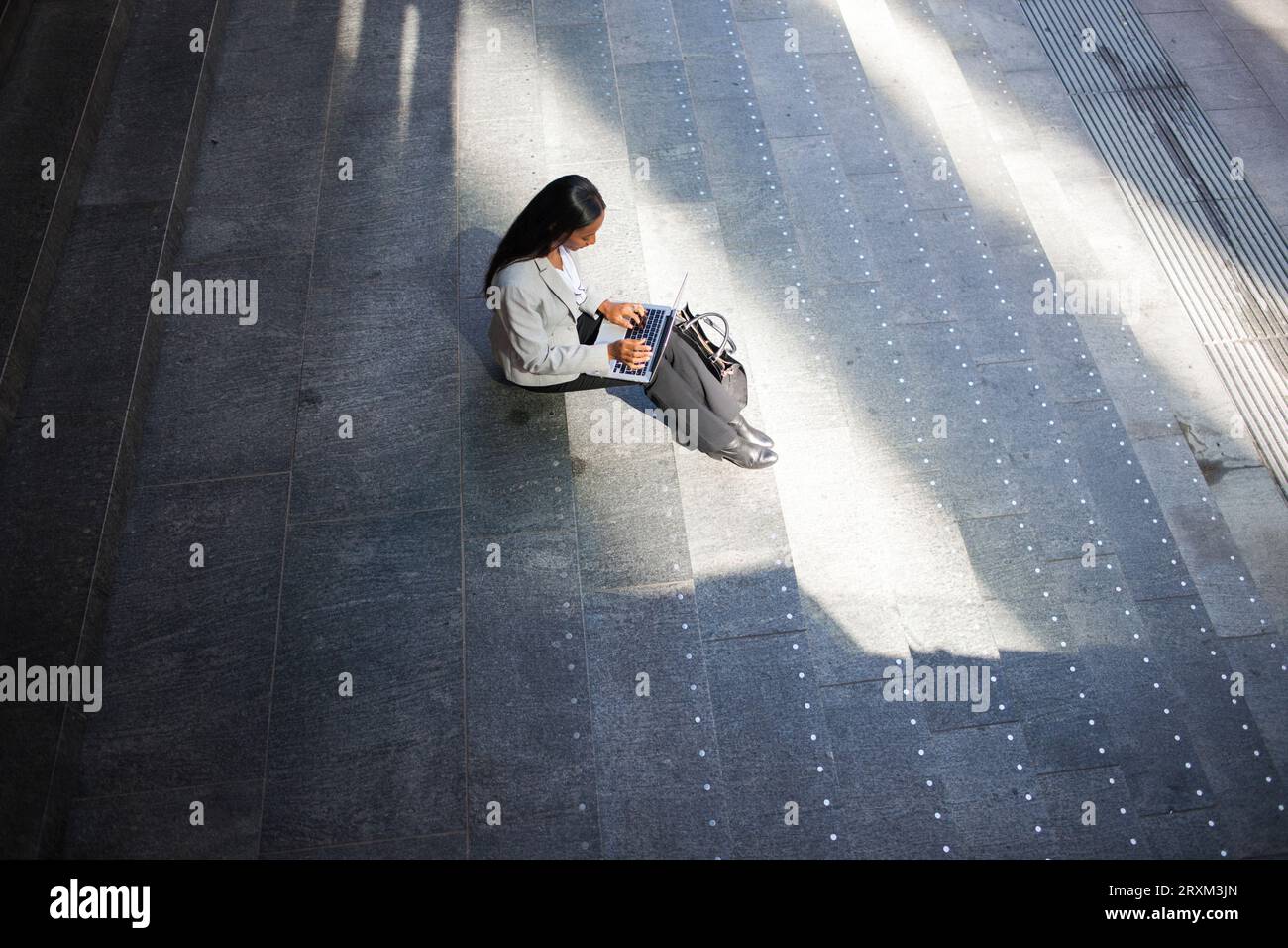 Vue à angle élevé de femme d'affaires utilisant un ordinateur portable sur l'escalier Banque D'Images