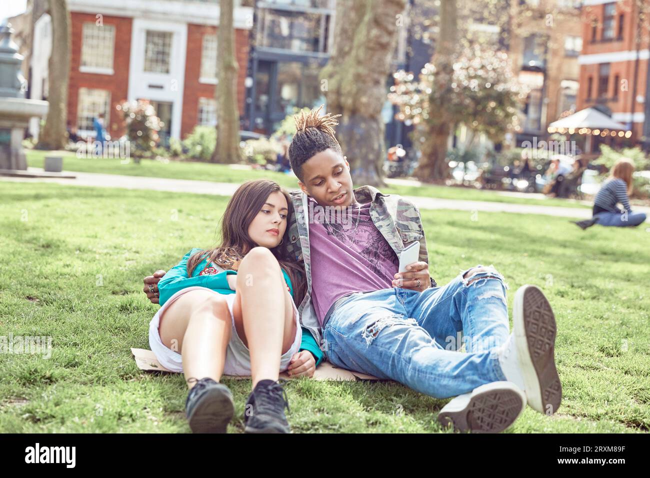 Teenage couple sitting together at park Banque D'Images