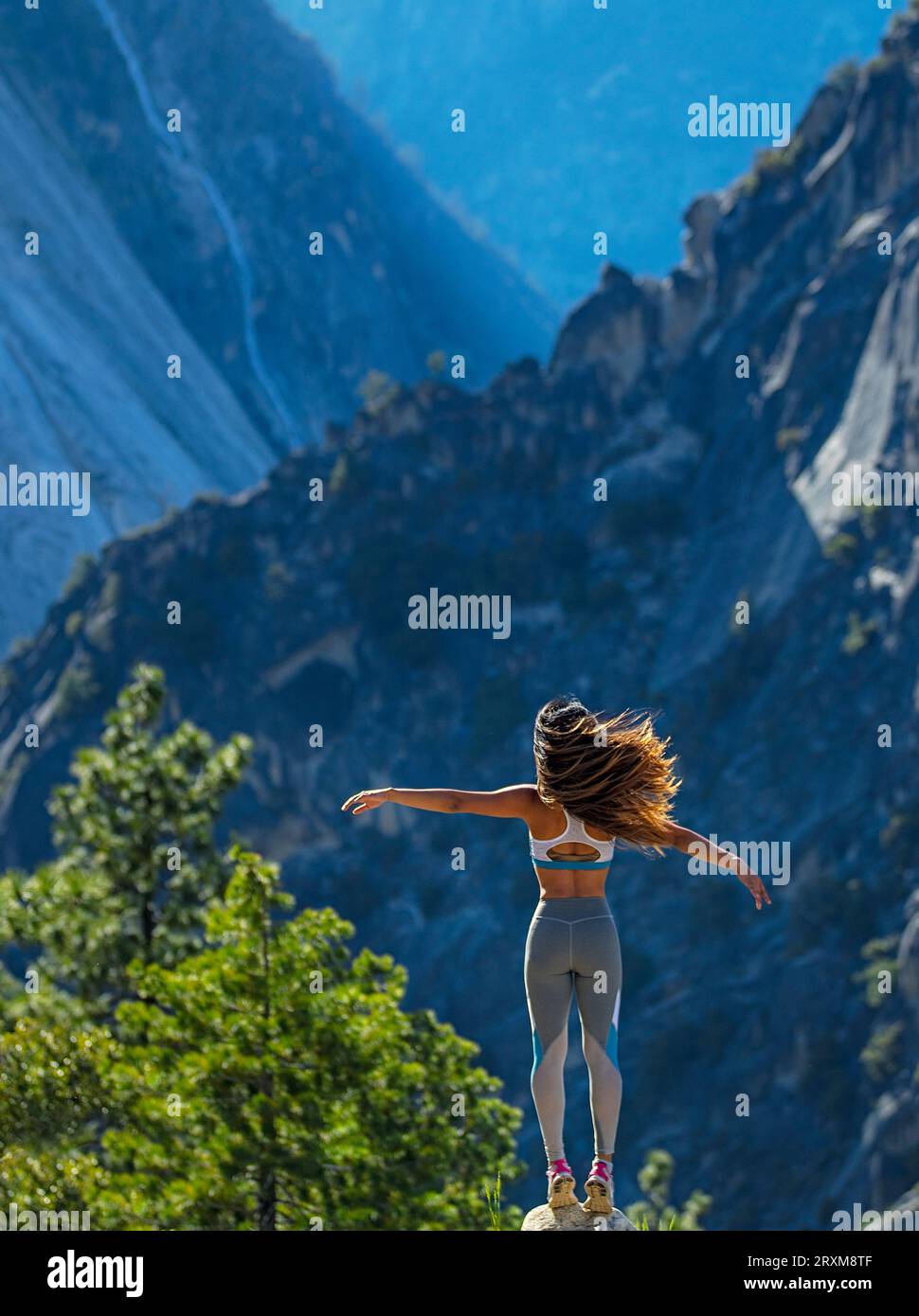 Jeune femme debout sur un rocher au pied d'une montagne Banque D'Images