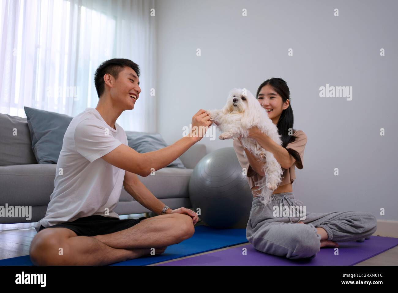 Un jeune couple joue au yoga à la maison. Concept de style de vie et d'activités de loisirs. Banque D'Images
