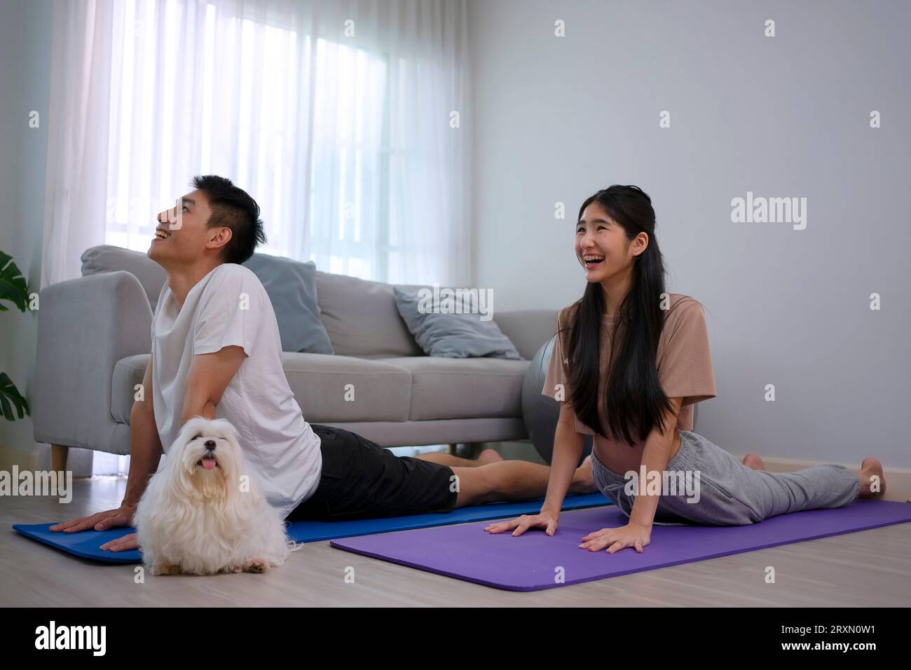 Un jeune couple joue au yoga à la maison. Concept de style de vie et d'activités de loisirs. Banque D'Images