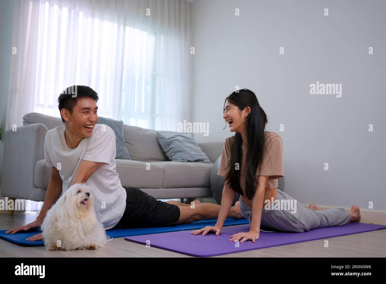 Un jeune couple joue au yoga à la maison. Concept de style de vie et d'activités de loisirs. Banque D'Images