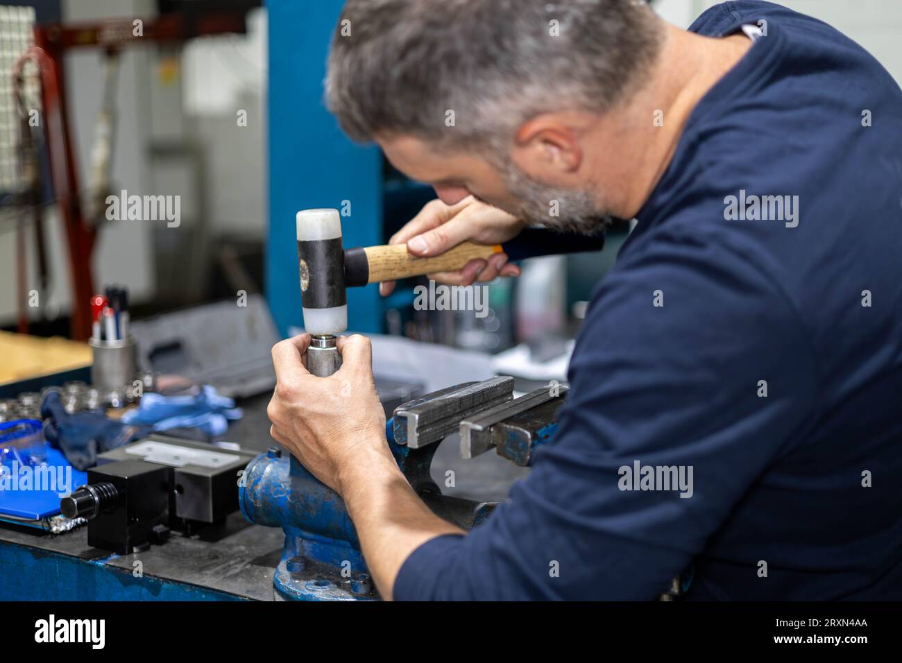 Travailleur professionnel travaillant sur une pièce d'acier avec marteau dans un atelier d'usine de métal. Mécanique industrielle machines et réparation. Banque D'Images