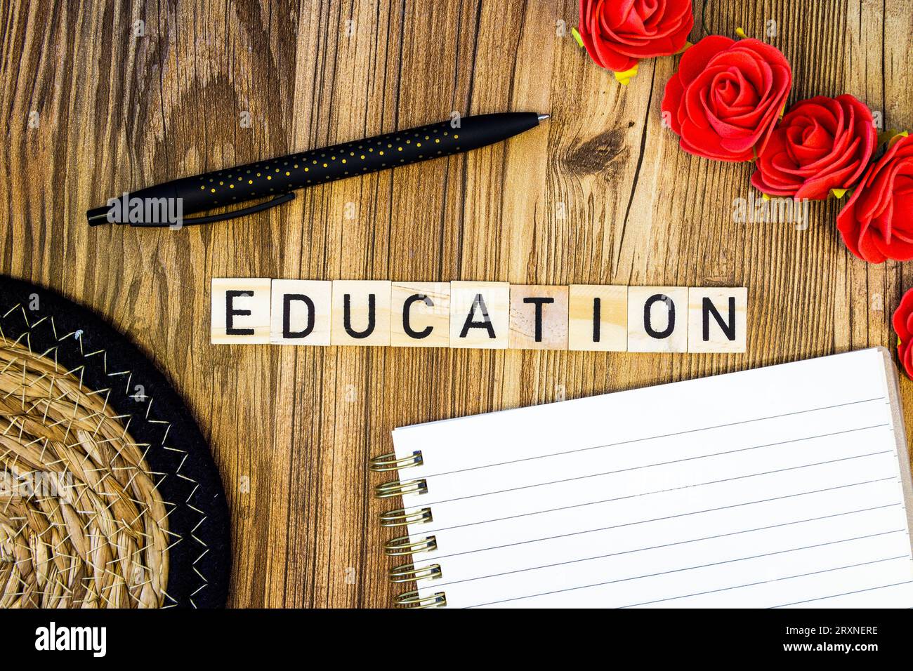 Éducation plat poser des lettres éparpillées avec cahier et stylo et tapis de paille et roses Banque D'Images