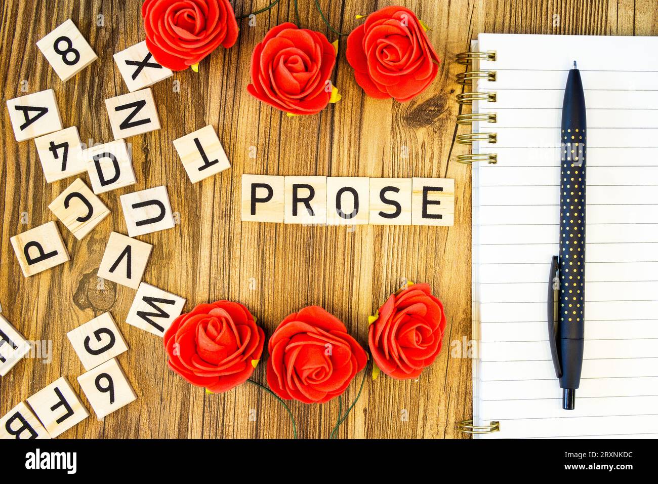 Pose plate en prose faite de lettres gravées au laser sur cahier de ligne vierge et stylo avec lettres éparpillées et roses Banque D'Images