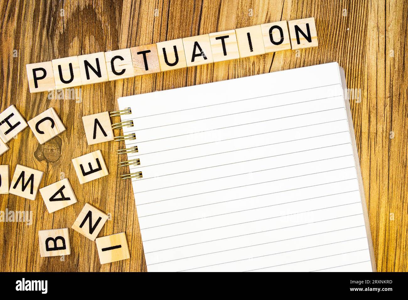 Ponctuation à plat faite de lettres gravées au laser sur un cahier de ligne vierge avec des lettres éparpillées Banque D'Images