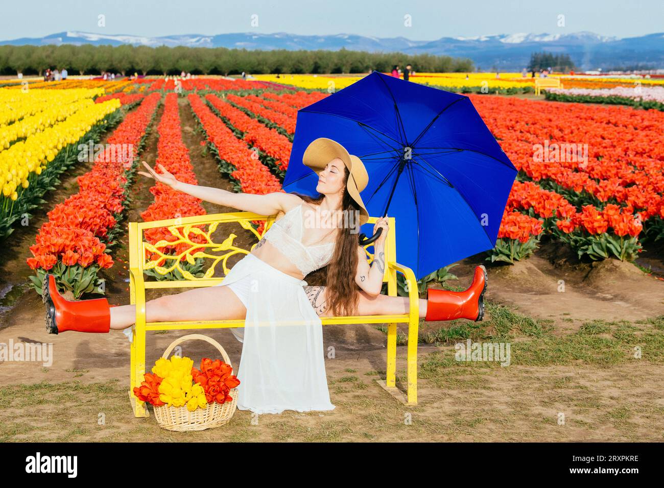 Brune aux cheveux longs se fendant sur le banc devant le champ de tulipes Banque D'Images