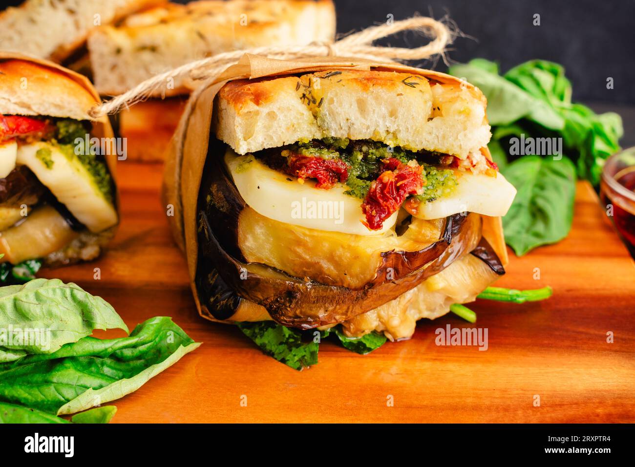 Sandwichs végétariens italiens grillés enveloppés dans du papier brun : sandwichs rustiques avec des ingrédients méditerranéens sur du pain focaccia grillé Banque D'Images