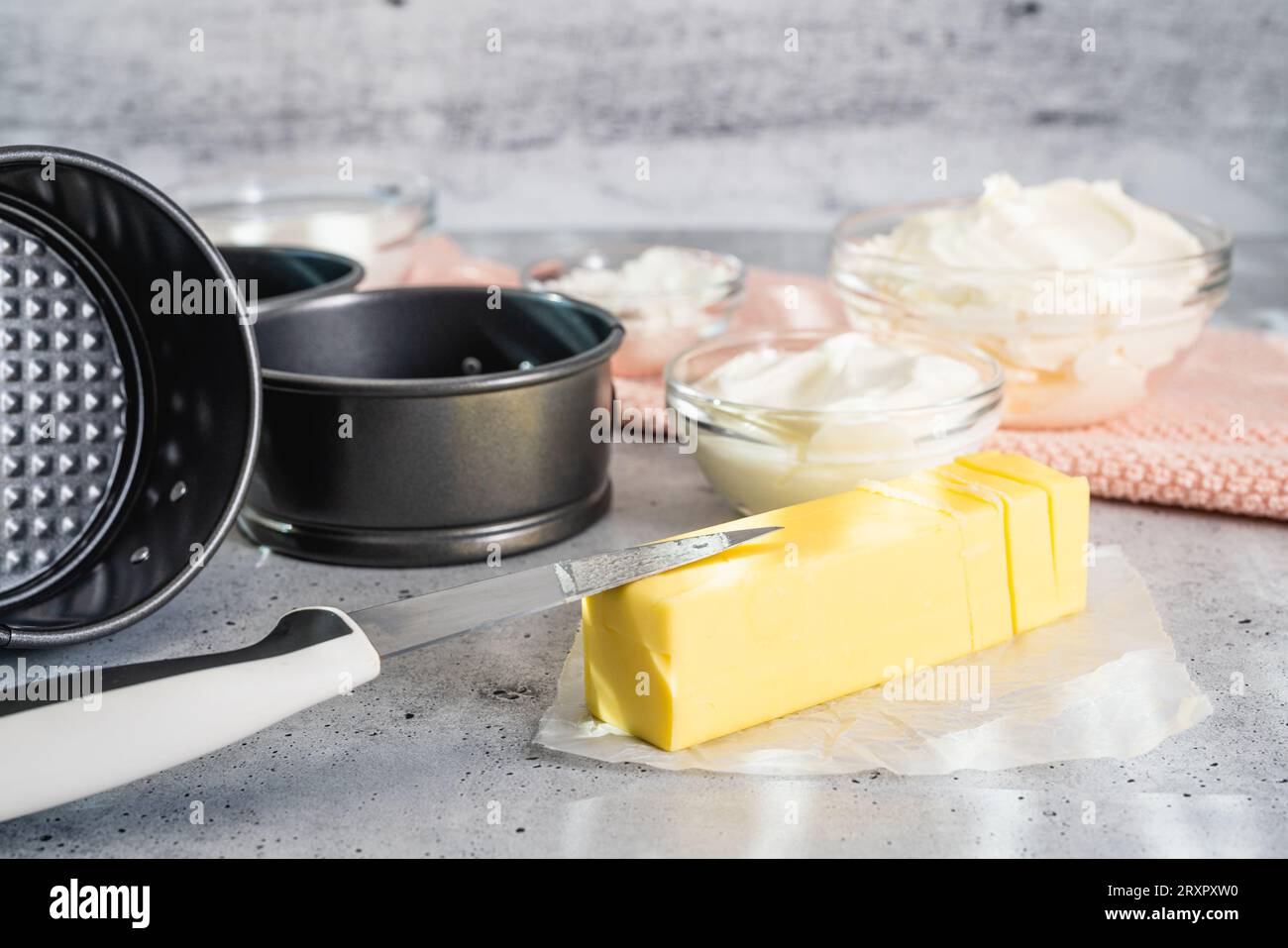 Recette de cheesecake. Trois mini moules à gâteau ronds (boîte, moule), du beurre et quelques ingrédients pour la recette de cheesecake gros plan sur la table de la cuisine Banque D'Images