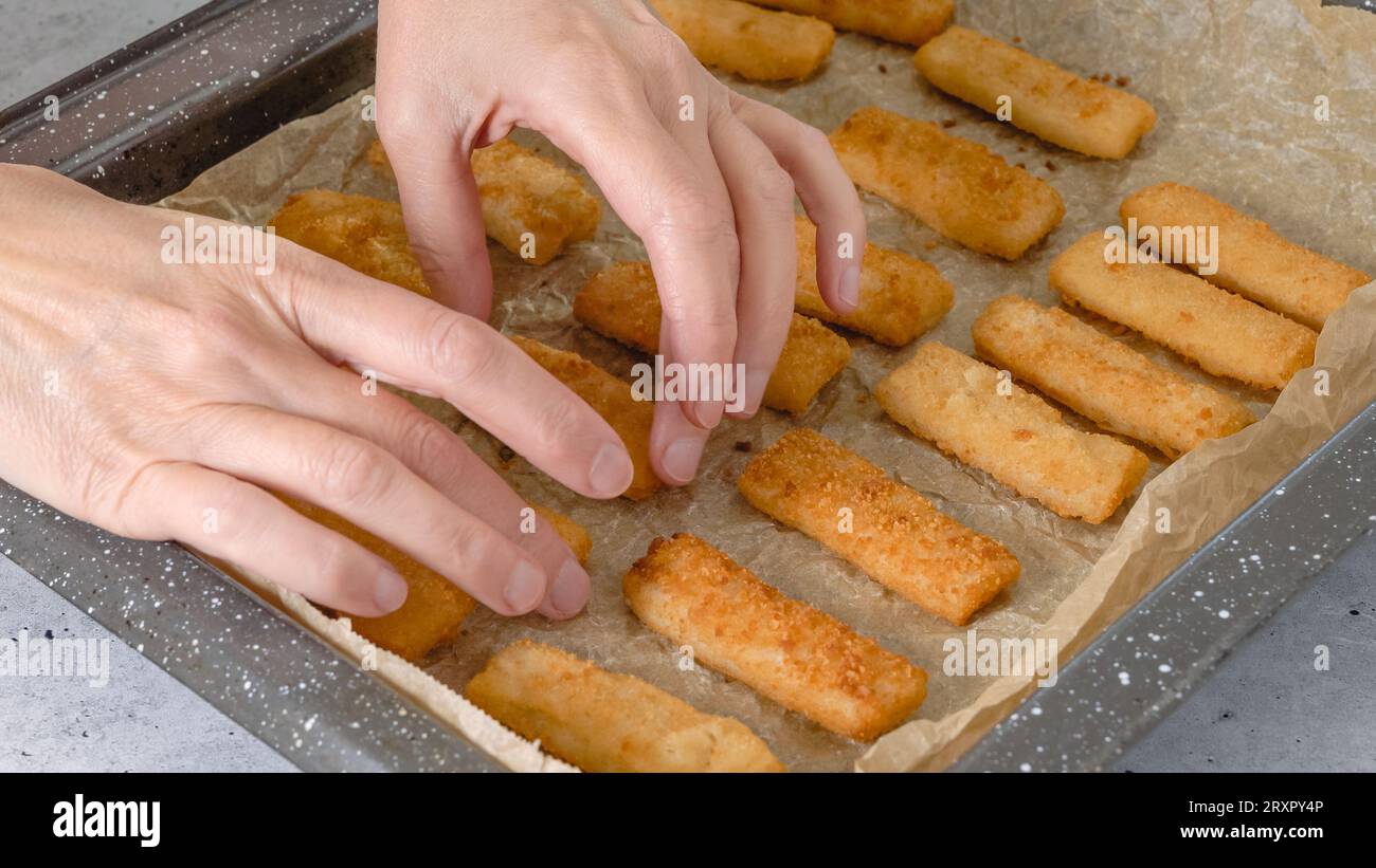 Plaque de cuisson avec bâtonnets de poisson sur la table de cuisine. Croquant délicieux, légèrement pané avec des bâtonnets de chapelure gros plan Banque D'Images