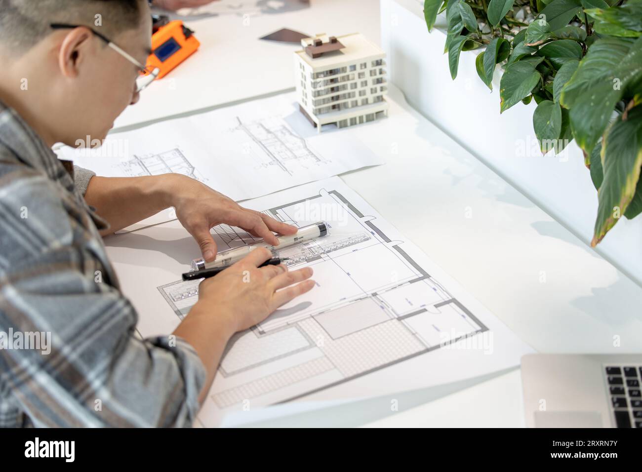 Homme architecte travaillant avec des plans modélisant la maison moderne. Banque D'Images