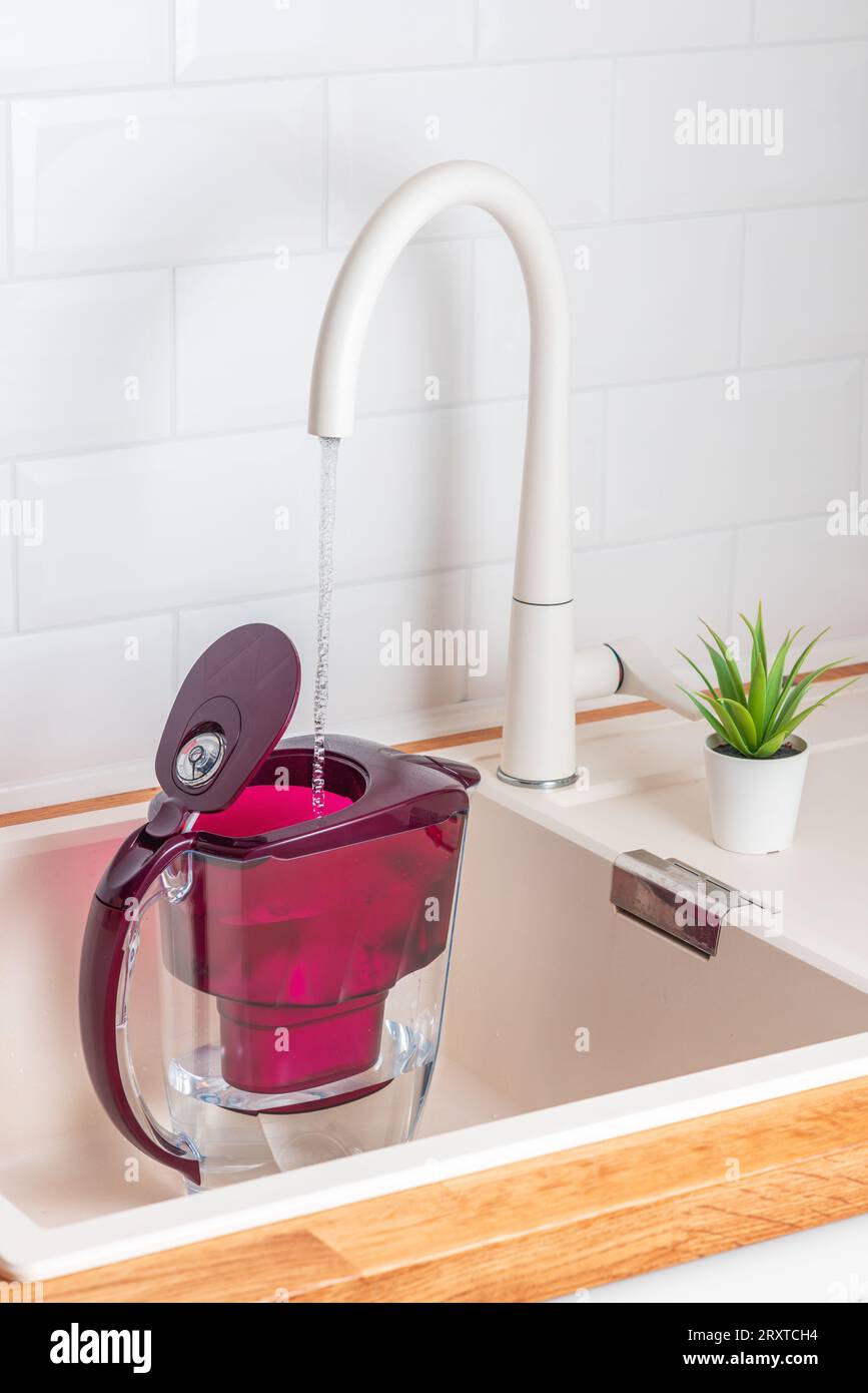 Verser de l'eau de la canalisation de la cuisine dans la cruche de filtration de l'eau, peut avec des filtres alcalins Banque D'Images
