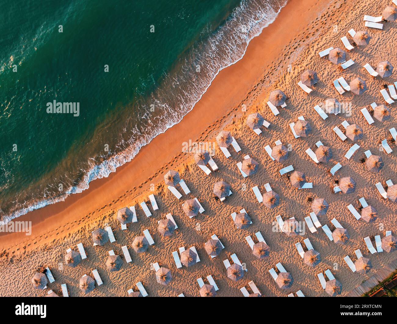 Vue aérienne de dessus de drone de plage de sable avec des vagues de mer turquoise, parasols et chaises longues avec espace de copie pour le texte Banque D'Images
