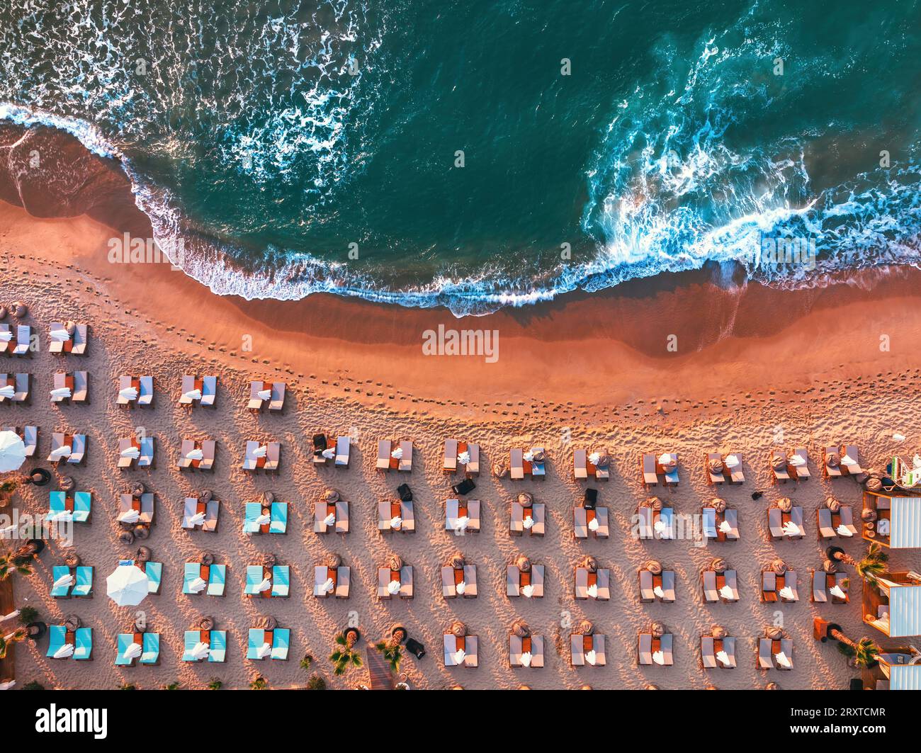 Vue aérienne de dessus sur la plage. Parasols, sable et vagues de mer pendant le lever du soleil panoramique Banque D'Images