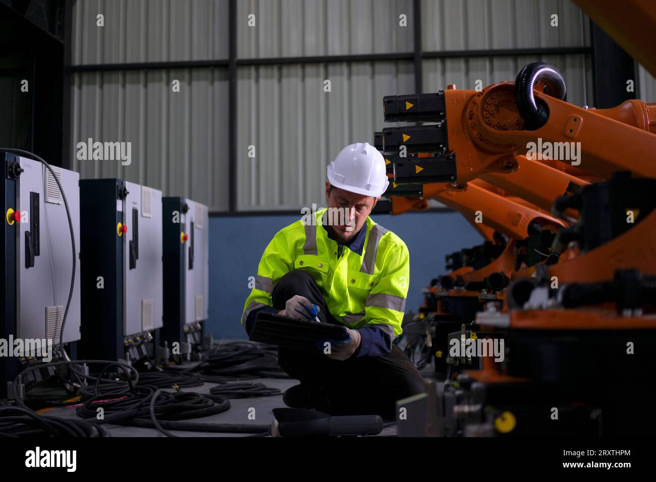 Un ingénieur travaille à l'usine de bras robotisés. Concept de technologie et d'ingénierie. Banque D'Images