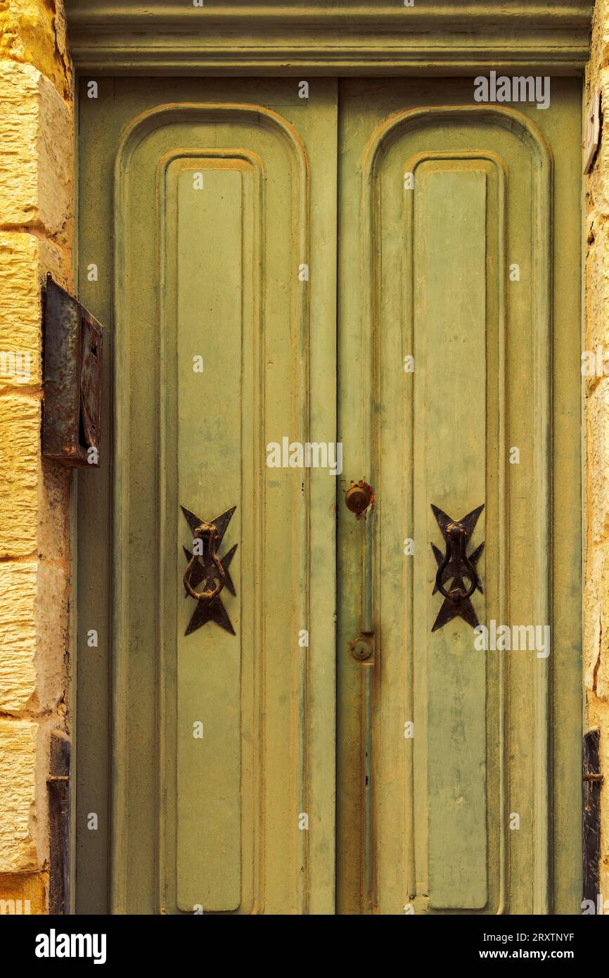 Heurtoirs de porte traditionnels en laiton avec la conception de croix maltaise à l'extérieur d'un bâtiment dans les ruelles de la vieille ville de Birgu (Citta Vittoriosa), Malte Banque D'Images