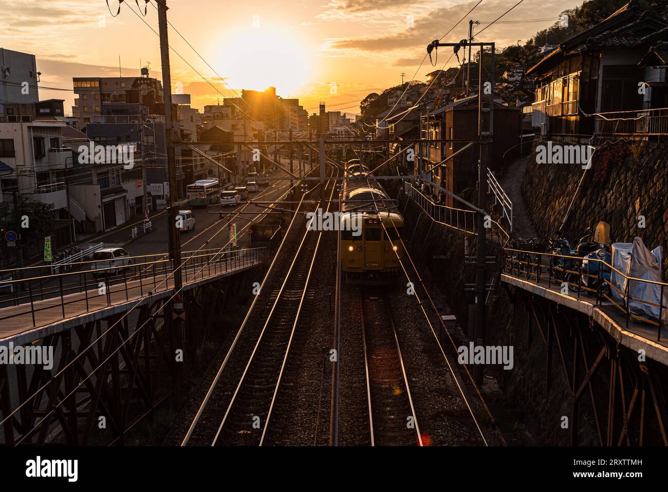 Vue depuis un pont ferroviaire avec un train japonais jaune approchant au coucher du soleil, Onomichi, Honshu, Japon, Asie Banque D'Images